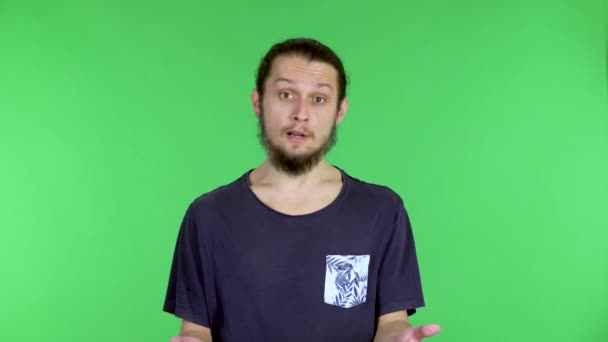 무엇인가에 손으로 말하고 가리키는 젊은이의 모습. 푸른 화면에 스튜디오에서 포즈를 취하고 있는 수염의 검은 머리 남자. 닫아. — 비디오