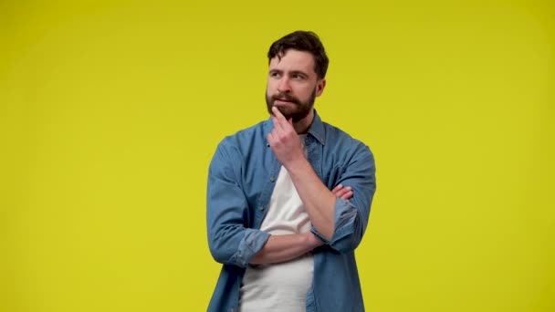 Portrait of a man, thinking intently, putting his hand on his chin, happily raising his index finger, an idea arose. A man in the studio on a yellow background. Close up. Slow motion ready 59.97fps. — Stock Video