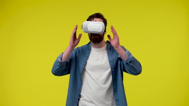Портрет человека с гарнитурой виртуальной реальности или 3D очками на голове. Мужчина в белой футболке и джинсовой рубашке в студии на жёлтом фоне. Закрывай. Готовность к медленному движению 59,97fps. — стоковое видео