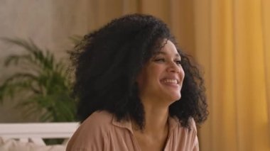 Afro-Amerikalı kadın ve kız mutlu bir şekilde oynayıp gülüyor. Anne ve kız poz veriyor, yatak odasında parlak bir iç mekan ile yatıyorlar. Kapatın. Yavaş çekim hazır, 4K 59.97 fps 'de..