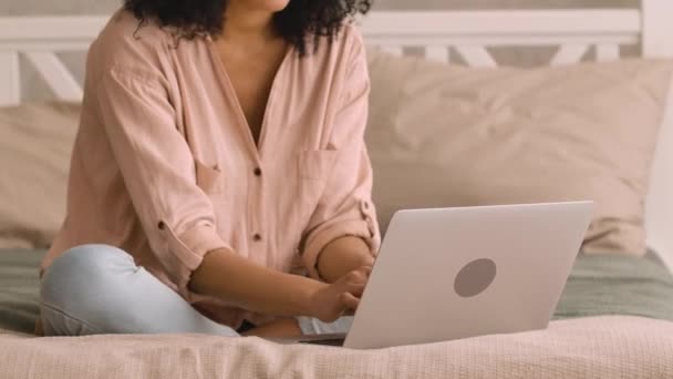 Retrato bonito afro-americano mulher estudando on-line ou trabalhando usando laptop. Ensino à distância, trabalho à distância. Mulher negra sentada na cama em quarto brilhante. Fecha. Movimento lento pronto, 4K a 59.97fps — Vídeo de Stock