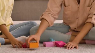 Afrika kökenli Amerikalı kadın ve küçük kız tahta oyuncak arabayla oynadılar ve inşaat setinden kule inşa ettiler. Anne ve kızı ışık odasında yerde oturuyor. Kapatın. Yavaş çekim hazır, 4K 59.97 fps 'de.