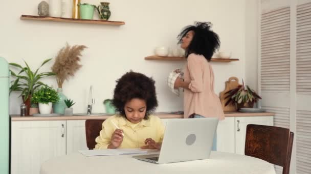 Een beetje gefocust Afrikaans schoolmeisje, bestudeert remote online vanuit huis, met behulp van laptop. Klein meisje leren op video klasse en maakt notities in een notebook. Slow motion klaar, 4K bij 59,97 fps. — Stockvideo