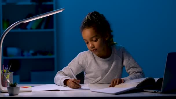 Девушка переписывает домашнее задание, широко зевает, кладет голову на руки, засыпает. Ребенок сидит за столом при свете ночной лампы. Закрывай. Готовность к медленному движению 59,97fps. — стоковое видео