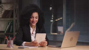 Dijital tablet kullanarak Afro-Amerikan konuşmalarının videodaki portresi, yeni bir proje ya da anlaşma üzerinde tartışır. İş kadını iş yerinde poz veriyor, ofiste masada oturuyor. Yavaş çekim hazır 59.94fps.