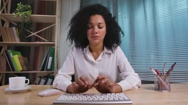 Retrato de mujer afroamericana escribiendo en el teclado de la computadora, mirando directamente al monitor. Empresaria posando en el lugar de trabajo, sentada a la mesa en la oficina. Vista de cámara web. Cámara lenta lista 59.94fps. — Vídeo de stock