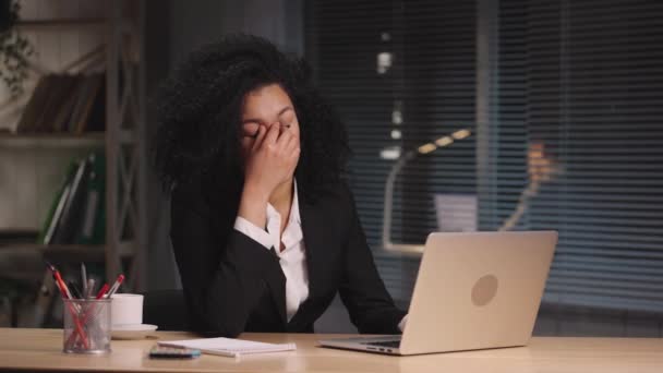 A fáradt afro-amerikai nő portréja túlterhelt és fejfájásban szenved. Üzletasszony pózol a munkahelyén, az asztalnál ül az iroda belsejében. Lassú mozgás kész 59.94fps. — Stock videók