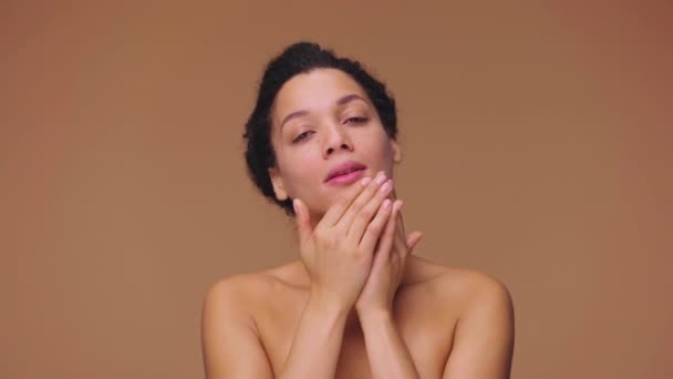 Portrait de beauté de jeune femme afro-américaine touchant doucement le visage avec les doigts et donnant massage de la peau. Femme noire posant sur fond de studio brun. Prêt au ralenti, 4K à 59.94fps. — Video