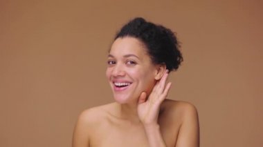 Genç Afro-Amerikan bir kadının güzel portresi. Kulak dibinde el ele tutuşup, haberleri ve dedikoduları dinlemeye çalışıyor. Kahverengi stüdyo arka planında poz veren siyah bir kadın model. Yavaş çekim hazır, 4K 59.94fps 'de..