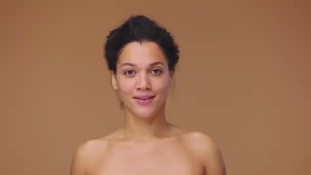 Krásný portrét mladé Afroameričanky držící napůl grapefruit a pleťový krém, volící. Černá žena na pozadí hnědého studia. Zpomalení připraveno, 4K při 59,94fps. — Stock video