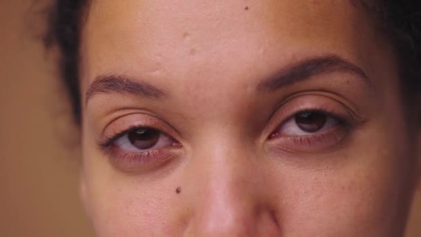 Les yeux bruns des femmes regardent droit devant elles sérieusement. Femme afro-américaine les yeux avec une beauté naturelle. Gros plan macro portrait avec une peau parfaite propre et lisse. Prêt au ralenti, 4K à 59.94fps. — Video