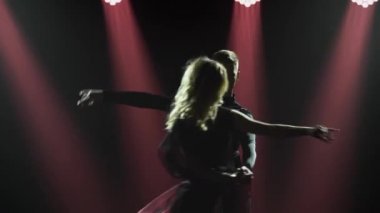 Rumba genç ve zarif bir çift tarafından seslendirildi. Dans partnerlerinin siluetleri karanlık bir stüdyoda arka planda Latin Amerika dansları yapıyor. Kapat..