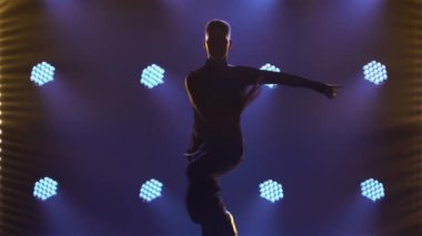 Rumba yapan bir erkek dansçının silueti. Balo dansçısı karanlık bir stüdyoda duman ve ışıklarla parke üzerinde Latin Amerika dansları yapıyor. Kapat..