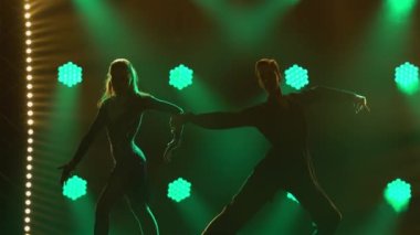 Rumba, samba, cha-cha-cha, jive. Bir çift profesyonel dansçı, karanlık bir stüdyoda yeşil neon ışıkların önünde tutkuyla dans ediyor. Siluetler. Kapat..