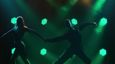 Rumba, samba, cha-cha-cha, jive. Bir çift profesyonel dansçı, karanlık bir stüdyoda yeşil neon ışıkların önünde tutkuyla dans ediyor. Siluetler. Kapat..
