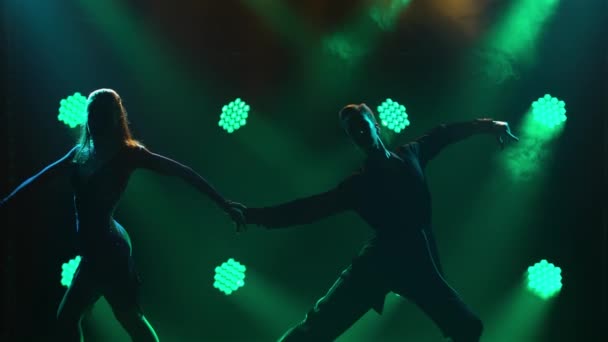 Rumba, samba, cha-cha-cha, jive. Een paar professionele dansers die hartstochtelijk dansen in een donkere studio tegen een achtergrond van groene neonlichten. Silhouetten. Sluiten.. — Stockvideo