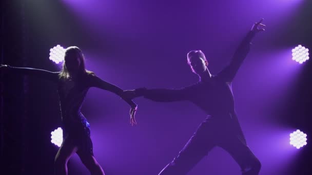 Επαγγελματική παράσταση χορευτών στο πρόγραμμα χορού της Λατινικής Αμερικής. Σιλουέτες αισθησιακού ζευγαριού σε φόντο μωβ φώτων σε σκοτεινό καπνιστό στούντιο. Κλείσε.. — Αρχείο Βίντεο