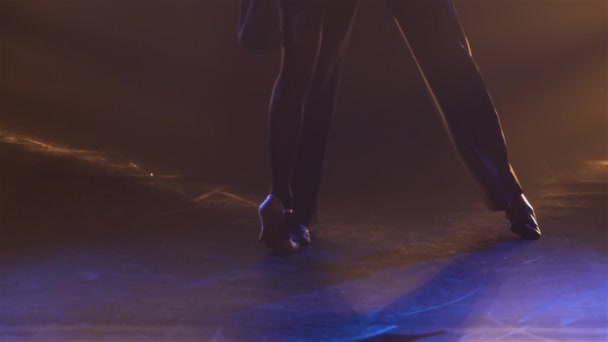 Sensuell rumba dans som utförs av par professionella balsalsdansare. En man och en kvinna dansar med sina kroppar hopkurade i en mörk ateljé med rök och gult ljus. Närbild. Långsamma rörelser. — Stockvideo