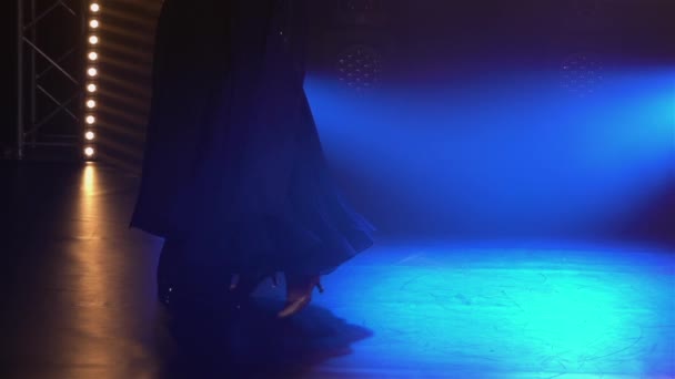 Элегантная пара танцовщиц танцующих вальс, прыгающих и держащихся за руки. мужчина и женщина вальсируют в темной студии среди ярких синих прожекторов и дыма. Закрывай. замедленное движение. — стоковое видео