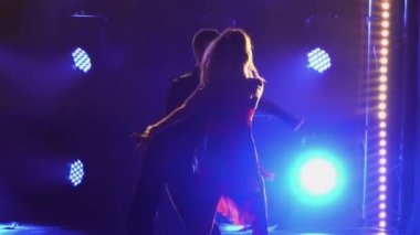 Yangın çıkaran rumba, balo dansçıları tarafından icra ediliyor. Takım elbiseli bir adam ve kısa elbiseli bir kadın, parlak mavi ışıklı, karanlık bir stüdyoda tutkuyla dans ediyorlar. Siluetler. Kapatın. Yavaş çekim.