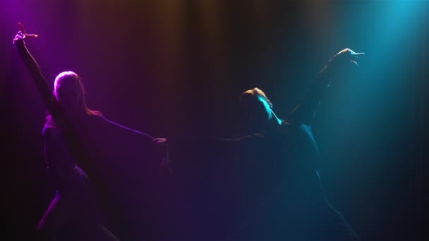 Silhouette dancing couple will emerge from darkness and smoke. Man and woman passionately dancing rumba elements against backdrop of beautiful blue violet rays of studio light. Close up. Slow motion. — Stock Video