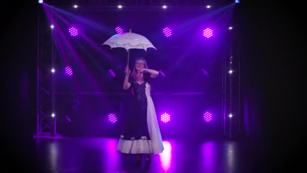 Vogeltrucs. Een vrouw draait een kanten paraplu, waarop wit getrainde duiven zitten en in een cirkel lopen. Professionele circus show met vogels in een donkere studio tegen een achtergrond van paarse lichten. — Stockvideo