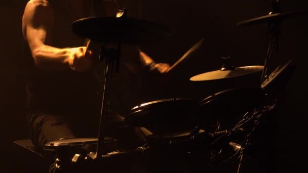 Músico profesional tocando tambores y platillos de percusión en un oscuro estudio ahumado con luces amarillas. Primer plano del torso del baterista golpea en el kit de batería. Concierto de rock, actuación en vivo. Silueta. — Vídeos de Stock