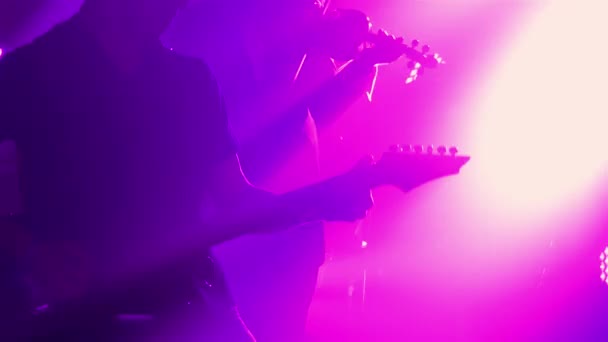 Energisk livekonsert av ett rockband. Ett team av musiker spelar dynamiskt fiol, elgitarr och trummor i mörkret mitt i röken och dynamiska lila ljus. Silhuett. Närbild. — Stockvideo