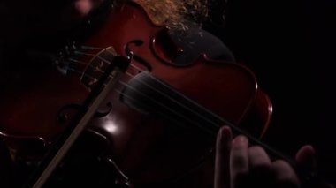 Klasik ahşap keman çalan kemancının detaylı görüntüleri. Bir adam bir melodi çalarken yayıyla kemanın tellerine dokunur. Virtüöz keman, siyah stüdyo arkaplanını kapat. Siluet.