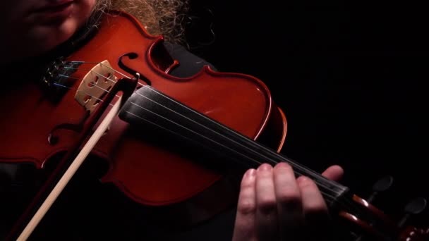 Detaljerade bilder av en violinist som spelar en klassisk träfiol. En man rör vid strängarna på en fiol med sin båge medan han spelar en melodi. Virtuoso violin närbild på svart studio bakgrund. — Stockvideo