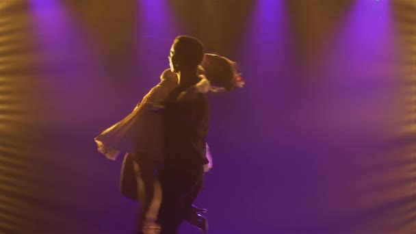 Een paar ballroom dansers dansen romantisch in een donkere studio tegen de achtergrond van felblauwe lichten. Silhouetten van een man en vrouw die elementen van rumba, salsa of flamenco dansen. Sluiten.. — Stockvideo