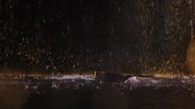 Tahta bir akustik gitar suyun yüzeyine çarpar ve bir sürü sıçrama yaratır. Yağmurda müzik aleti. Siyah stüdyo arka planında yağmur damlaları arasında gitar. Kapatın. Yavaş çekim.