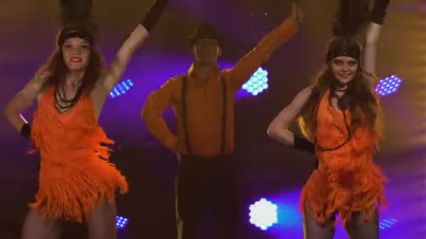 Grupo de baile vestido con trajes de estilo Chicago de los años 30 están bailando alegremente en el estudio con luces brillantes. Hombre con sombrero y mujer con vestidos cortos realizan espectáculo teatral en la fiesta. De cerca.. — Vídeo de stock