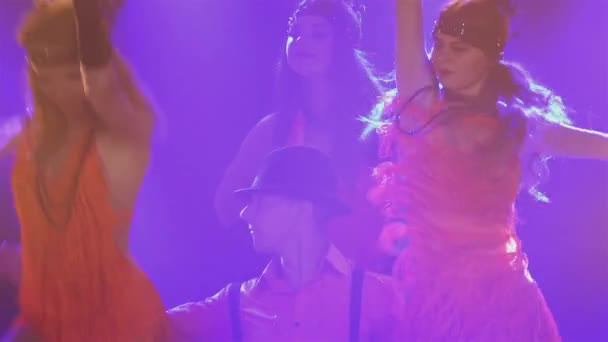 Un groupe de danse vêtu de costumes de style Chicago des années 30 danse joyeusement en studio avec des lumières vives. Homme en chapeau et femme en robes courtes effectuer spectacle théâtral à la fête. Gros plan. — Video