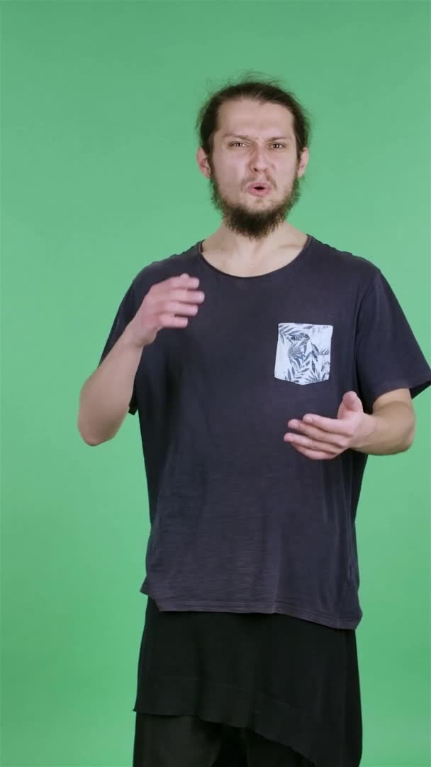 Retrato de un joven mirando a la cámara y celebrando su victoria bailando el baile de los ganadores. Un hombre moreno con barba en el estudio en una pantalla verde. En cámara lenta. Vídeo vertical. — Vídeos de Stock