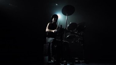 Bateri ve perküsyon zilleri çalan bir rock müzisyeninin alt görüntüsü. Davulcu, havalı bir canlı rock konseri yaratmak için bagetlerin ustasıdır. Işık huzmesinin merkezinde bir siluet.