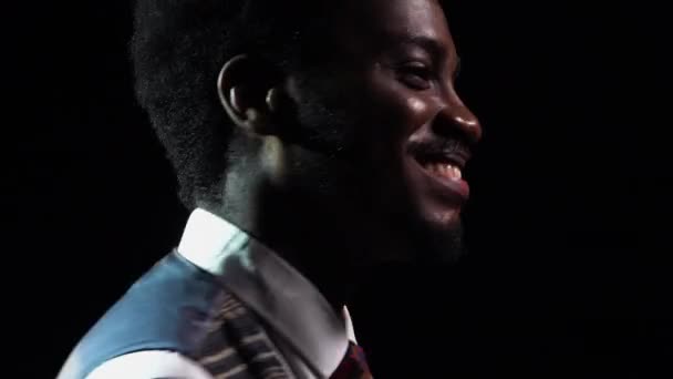 Hombre afroamericano con elegante traje retro canta una canción y gestos con sus manos. Un intérprete de jazz actúa en un estudio oscuro con luces brillantes. Música étnica africana. De cerca.. — Vídeo de stock