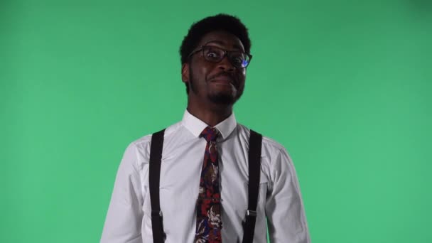 Portret młodego Afroamerykanina patrzącego w kamerę, uśmiechającego się i pokazującego kciuki w górę. Czarny mężczyzna w krawacie i okularach w białej koszuli pozujący na zielonym ekranie w studio. Zamknij się.. — Wideo stockowe