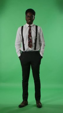 Portre genç Afrikalı Amerikalı adam rapor veriyor ve bir sürü ilginç bilgi veriyor. Stüdyoda yeşil ekranda poz veren kravatlı ve gözlüklü siyah bir erkek. Dikey video.