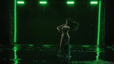 Egzotik oryantal dansçı, gölgede dans eden göbek dansçısıdır. Karanlık stüdyoda yağmur damlaları arasında yeşil ışıkla dans eder. Esnek kadın dans ederken kıvranıyor, şehvetli vücudunu gösteriyor. Yavaş çekim.