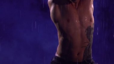 Çağdaş bale, insanoğlu yağmur altında yüzeyde duran modern koreografinin elementlerini sergiliyor. Çıplak vücutlu erkek dansçının şehvetli hareketleri. Siluet. Kapatın. Yavaş çekim.