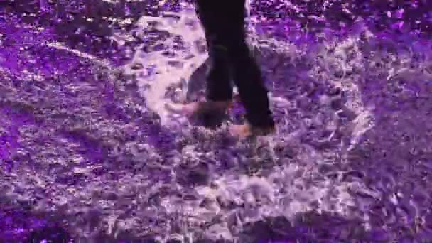Top view of wet man dancing sensual modern ballet on water surface in the rain. Romantic contemporary choreography. Silhouette of dancer with naked torso in purple studio light. Close up. Slow motion. — 비디오