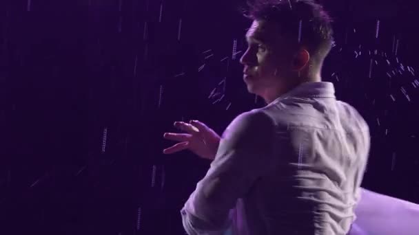 Emotionale Aufführung zeitgenössischer Ballettchoreographien im Regen in dunklem Studio mit blauem Licht. Silhouette eines nassen Mannes, der sich anmutig bewegt und akrobatische Elemente vorführt. Zeitlupe. Nahaufnahme. — Stockvideo