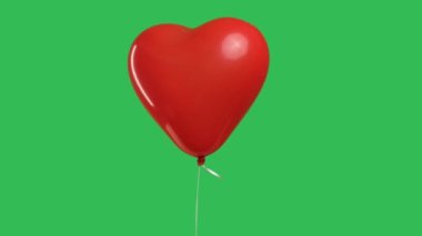 Kırmızı kalp şeklinde balon yeşil ekran krom anahtarının arka planında asılı duruyor. Aşk ve duyguların dışavurumu olarak bir balona yaklaş. Yavaş çekim.