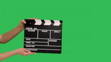 Movie clapper board clapped. Close up female hand hold empty black and white stripe film making movie slate isolated on green screen chroma key background studio. Slow motion.
