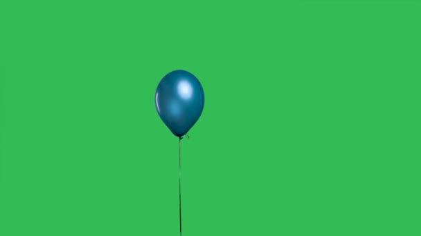 Balão azul pendurado no ar contra o fundo de uma chave croma tela verde. Balão de hélio colorido em uma fita. Aniversário, decoração da festa, férias, surpresa, presente. Movimento lento. — Vídeo de Stock