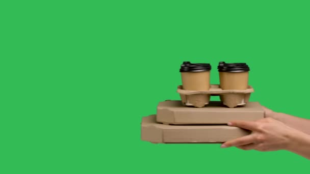 Female hands giving two cardboard box with pizza and set of paper cups with coffee on green screen chroma key. Close up of pizza and drinks. Fast courier delivery of food and drinks. Slow motion. — Stockvideo