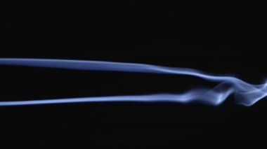 İki beyaz duman bulutlara karışıyor. Beyaz duman ve toz parçacıkları uzayda ağır çekimde siyah bir zemin üzerinde yüzerler. Kapat..