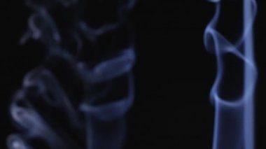 Ağır çekimde siyah arka planda duman, yüzen sis. Bulanık beyaz duman püskürtüleri yukarı doğru akar. Kapat..