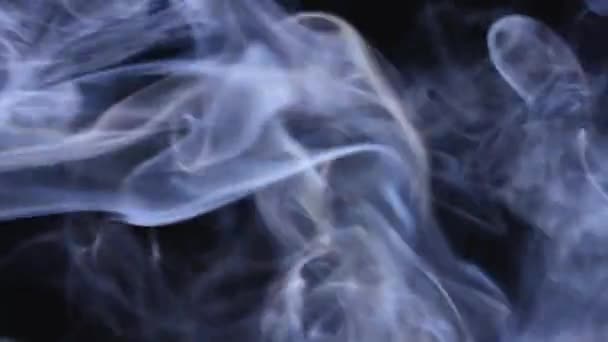 Moln av vit rök flyter i rymden. Snurrar av puffar av rök flöde utsmyckas mot en svart bakgrund i slow motion. Närbild. — Stockvideo